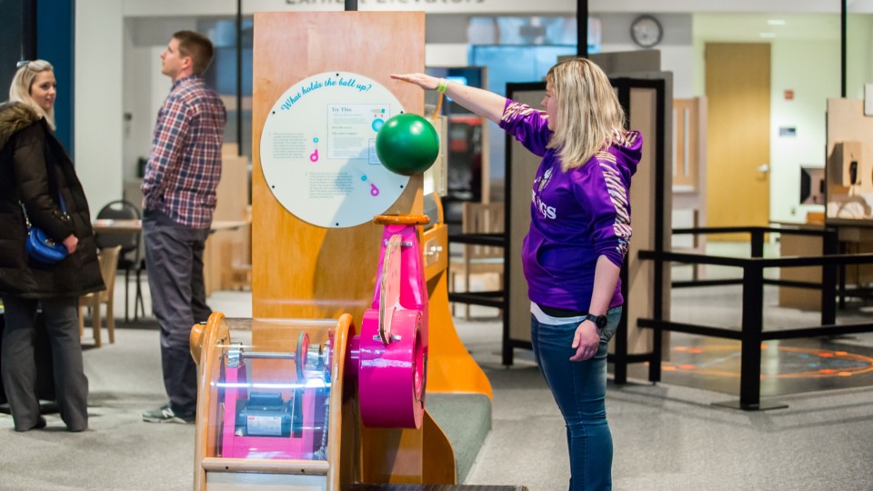 Woman using air to displace a ball in the experiment gallery