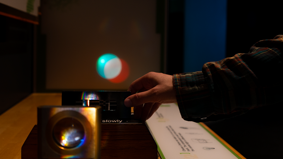 A hand manipulates an exhibit in the Light Gallery.