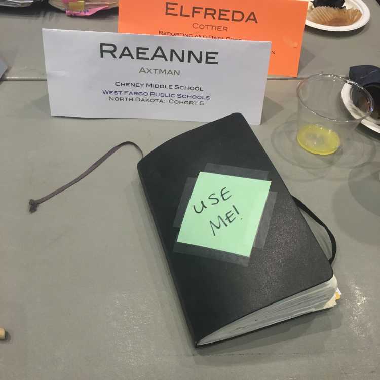 A photo of a notebook on a worktable with a note taped to it saying, "USE ME!"