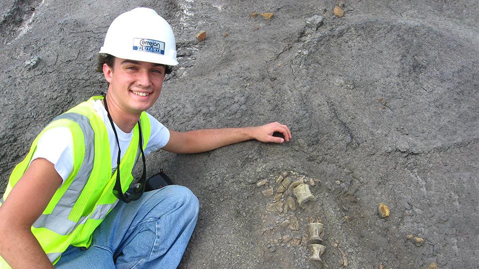 Dr. Alex Hastings poses next to a fossil. 