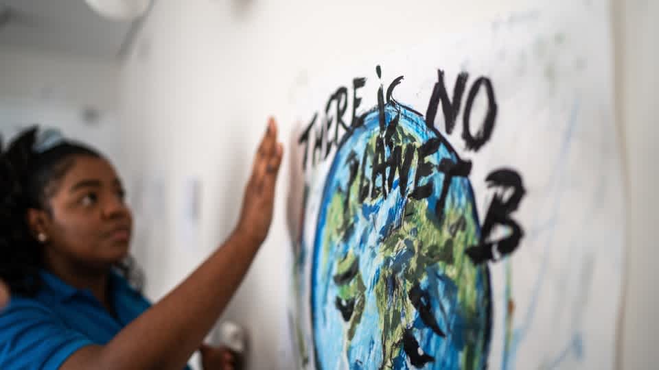 Student gesturing to a "There is no planet B" poster 