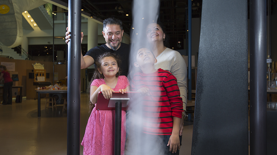 A family stands near the tornado activity, looking up at the swirling air