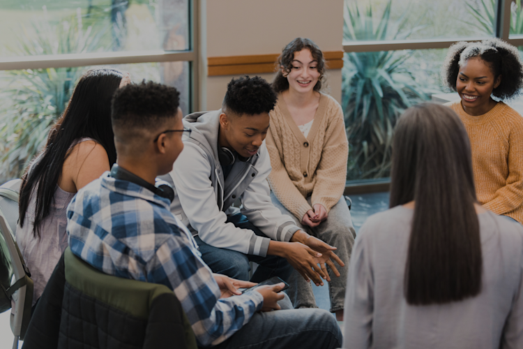 A group of young adults in a circle talking to each other in earnest conversation.
