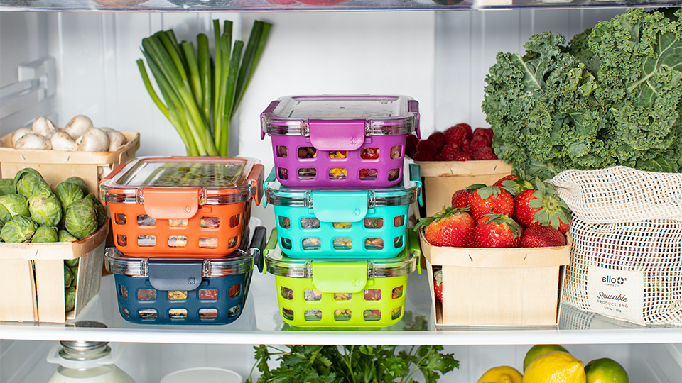 Baskets of fresh produce on a fridge shelf. 