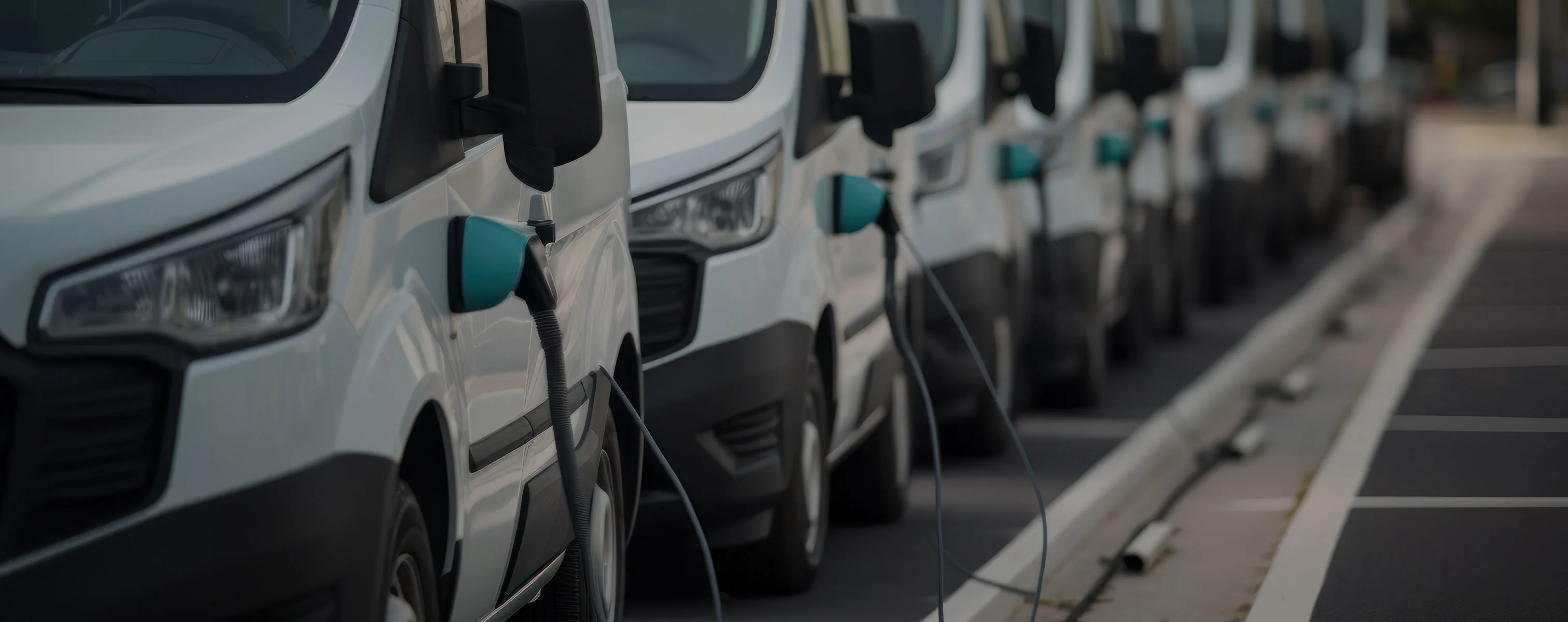 Rij witte elektrische bestelwagens die worden opgeladen.