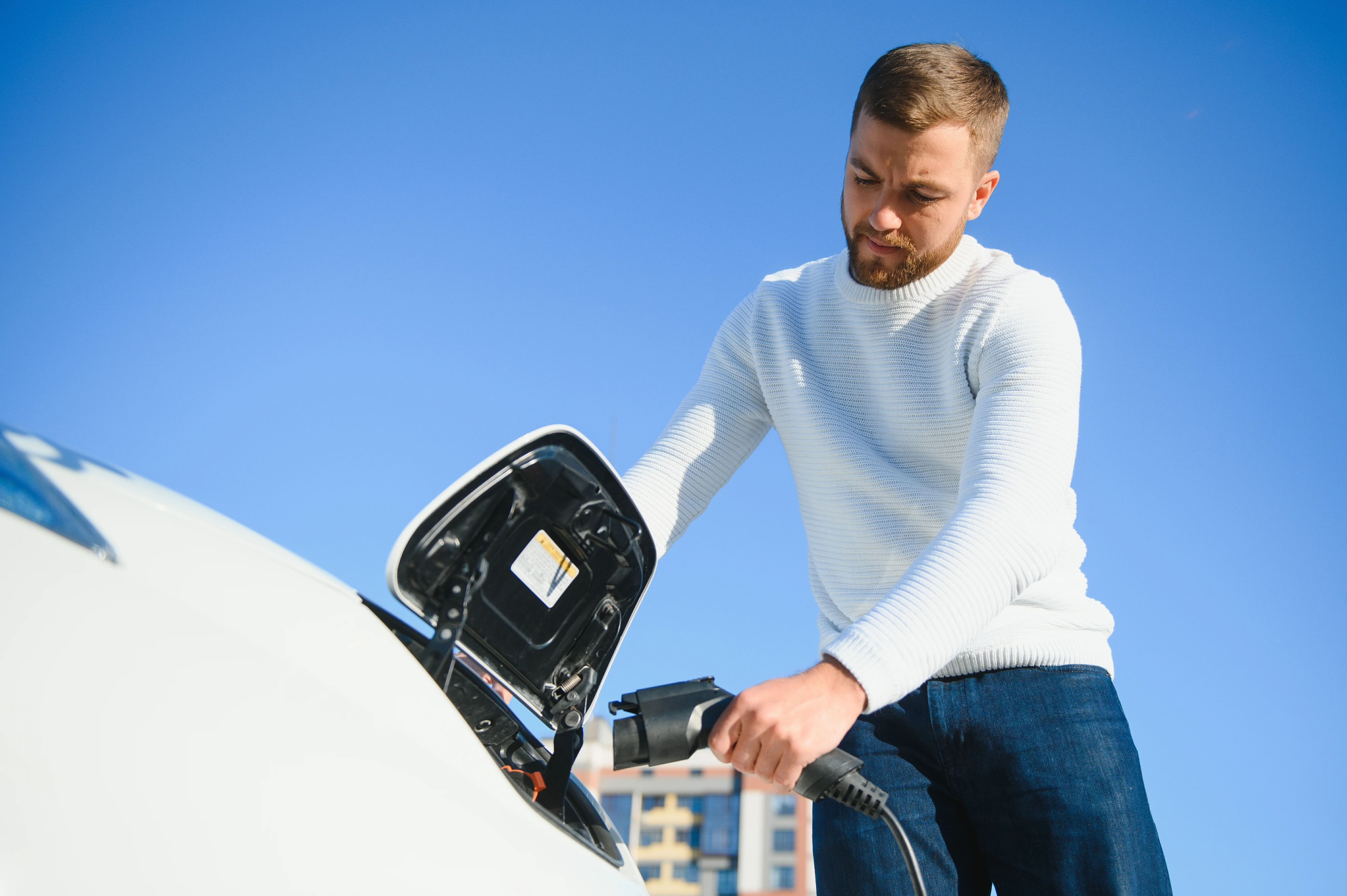 Eine Mann lädt ein Elektroauto auf.