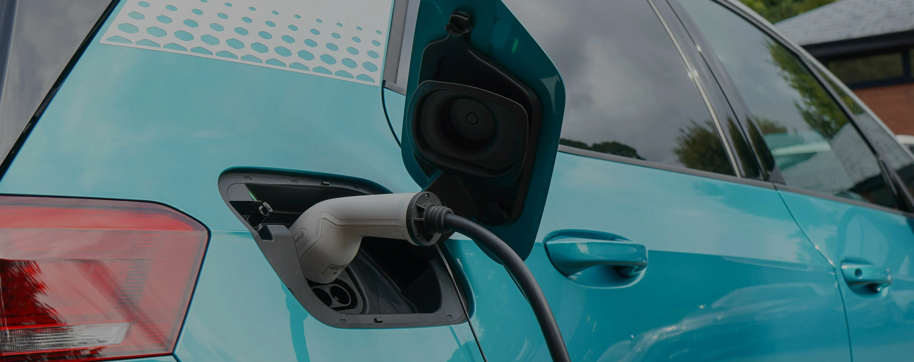 Une voiture électrique bleue est branchée à une borne de recharge publique.