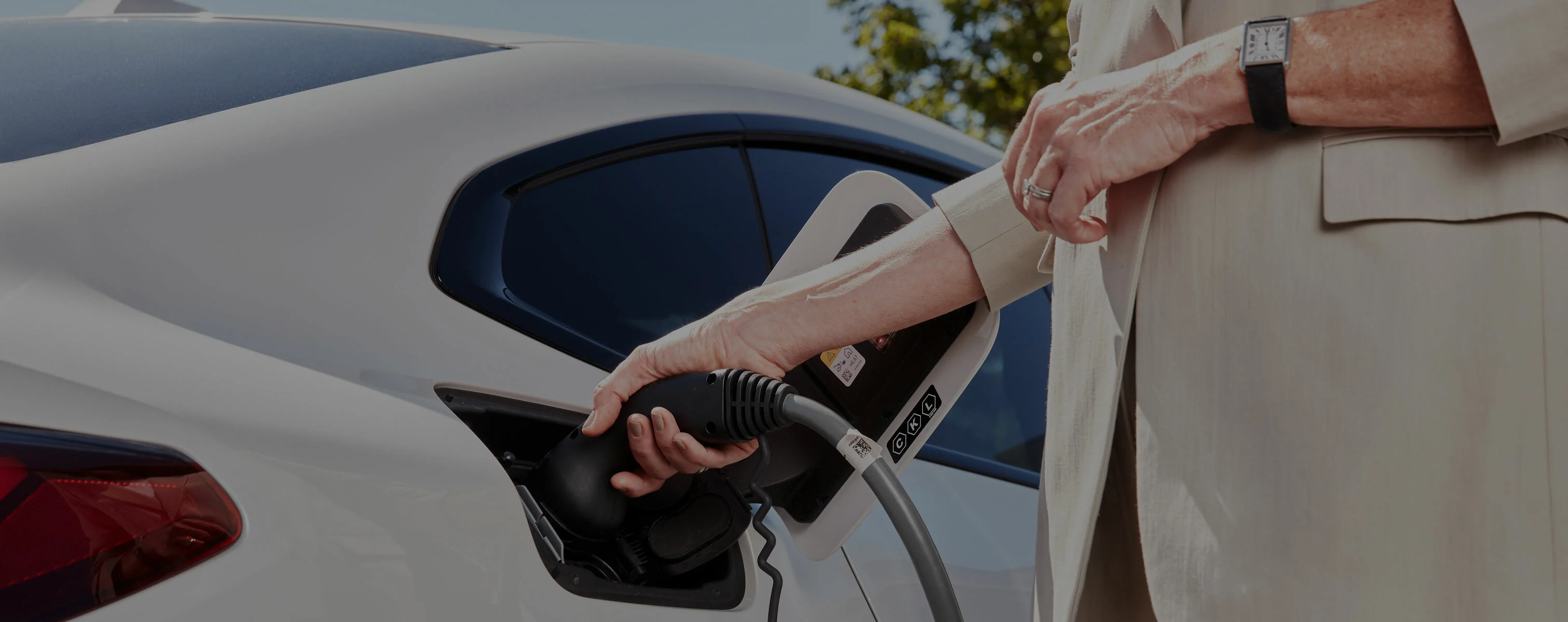 Person lädt ein Elektroauto mit einem Ladekabel auf.