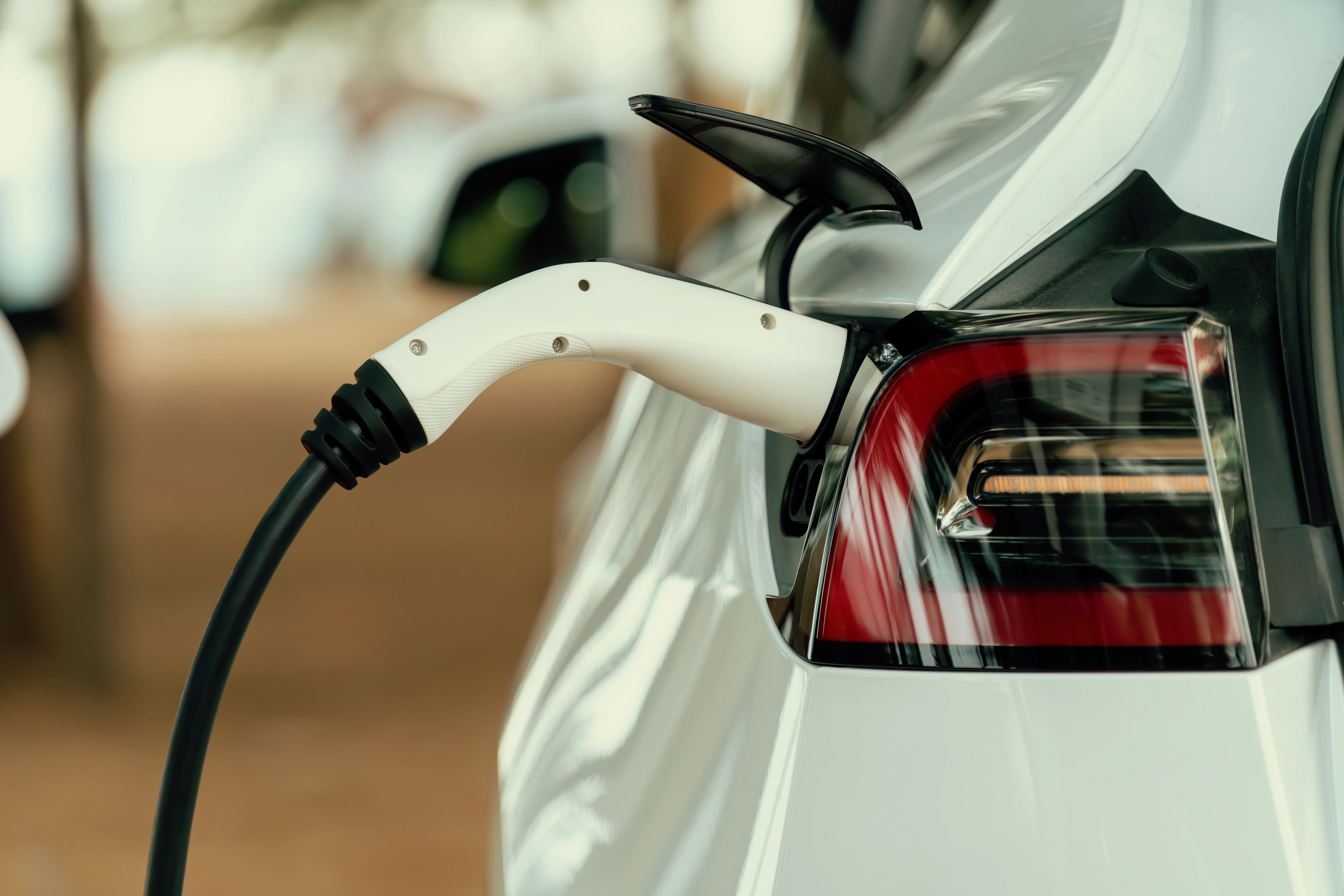 Gros plan sur une voiture blanche branchée à une borne de recharge.