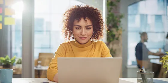 Femme souriante travaillant sur un ordinateur portable dans un bureau lumineux