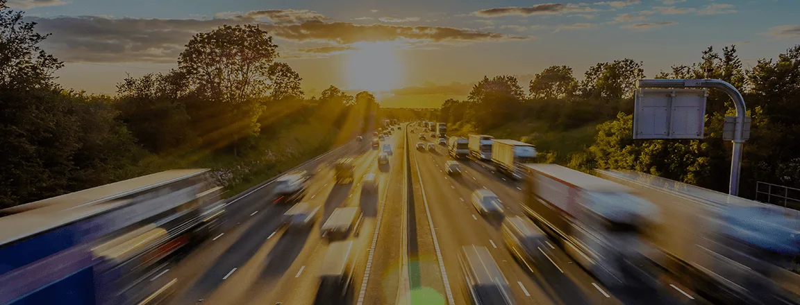 Vue d'une autoroute animée avec des camions et des voitures sous un coucher de soleil