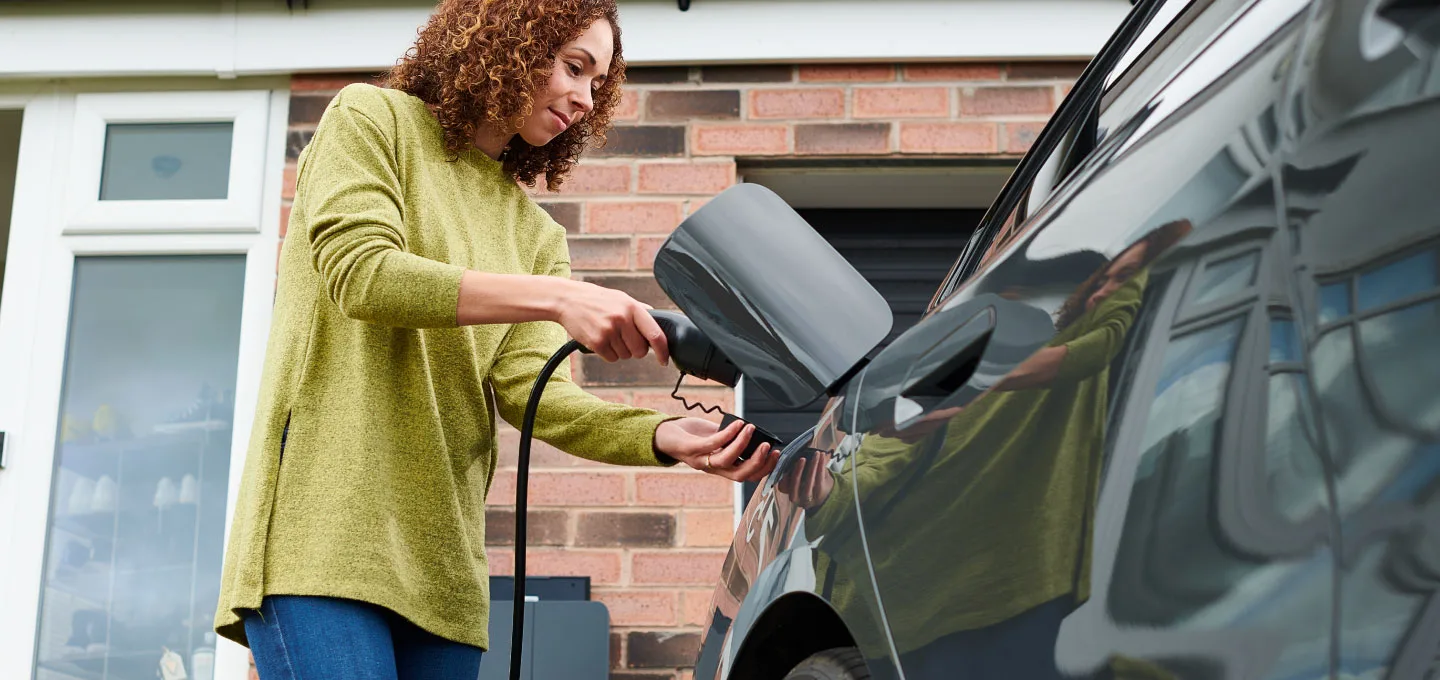 Eine Frau lädt ein Elektroauto auf.