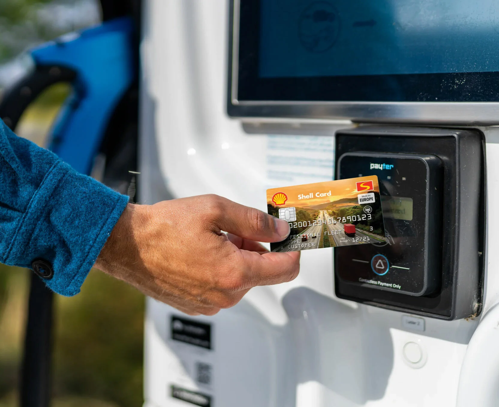 Hand hält eine Tankkarte an ein Lesegerät einer Ladesäule für Elektrofahrzeuge.