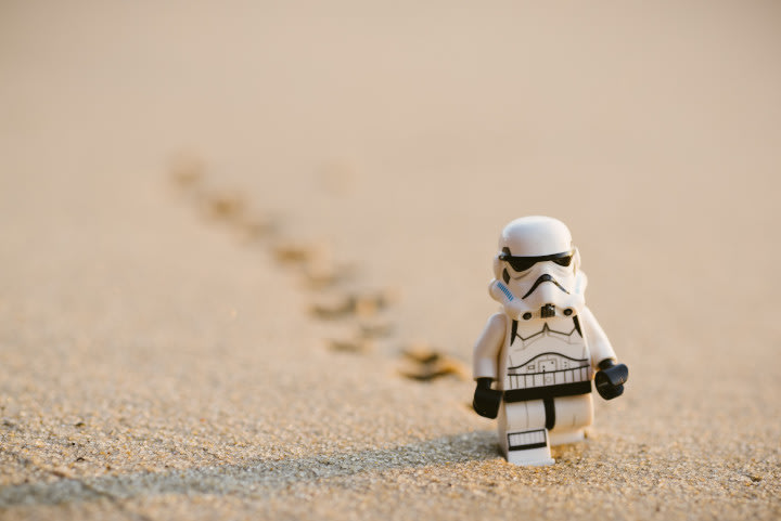 Single lego figure walking in sand