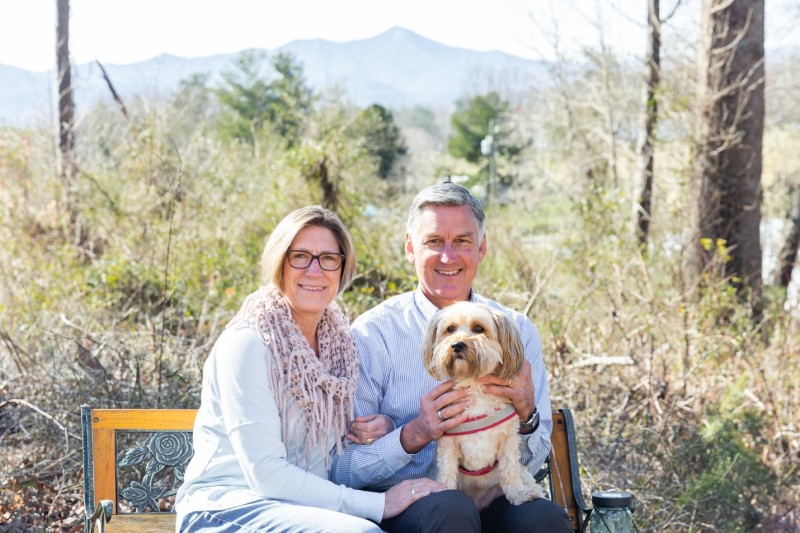 Katie and Rob Allyn sitting on a bench with their dog in their backyard in Asheville