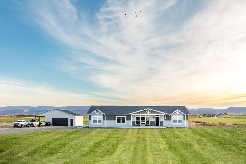 Beautiful manufactured home in the middle of some land with mountains in the background. 