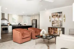 Manufactured home living room with kitchen in the background. Home is has white walls and is warm with natural light. The décor is burnt orange, white, and tan with a modern style.
