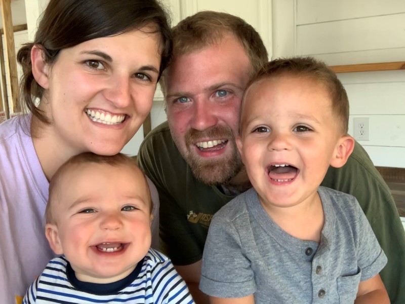 Woman, man, toddler and baby smiling at the camera.