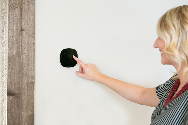 Woman programming a smart thermostat in her home.