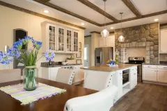 There's a kitchen and dining room in view. Kitchen has a stone alcove around the oven, there are white and wood accents throughout, and a kitchen island in the middle of the room.