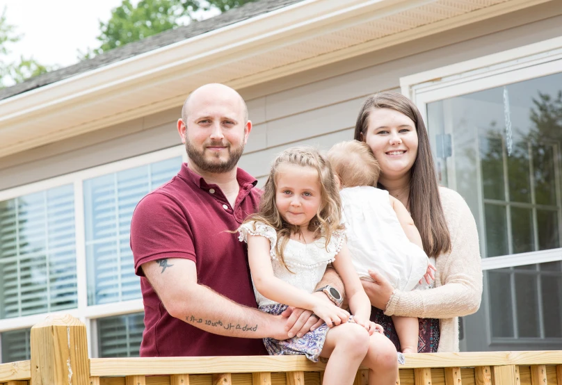 Woody family stands on the porch of their new home