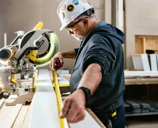 Clayton team member cuts wood with precision while building a modern manufactured home indoors.