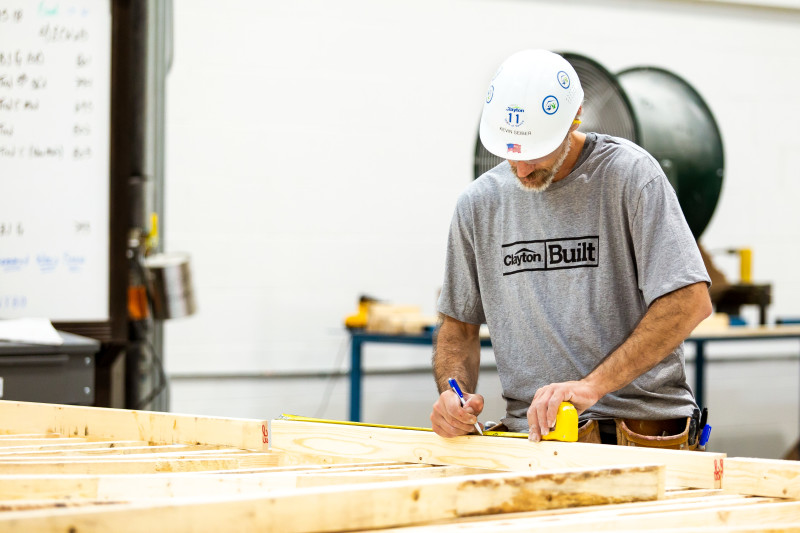 Clayton Built team member measuring wood for a home.