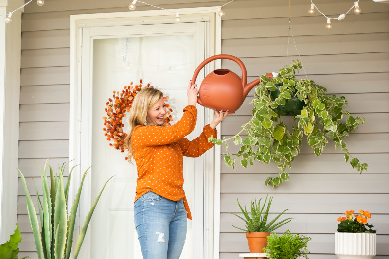 Women water her hanging plant outside her manufactured home.