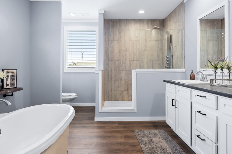 A primary bathroom suite with a walk-in shower, white vanity and freestanding tub