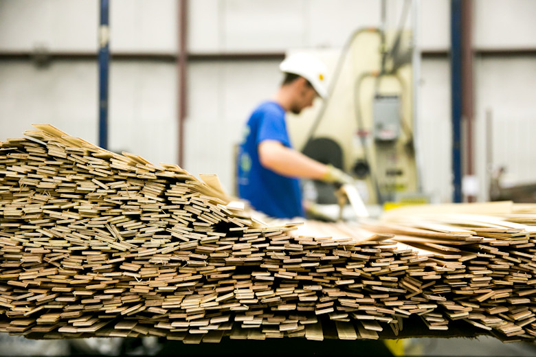 Manufactured home worker cutting wood strips.