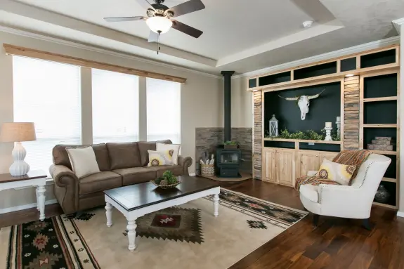 The living room of [model name] features a wood-burning stove option and built-in entertainment center.