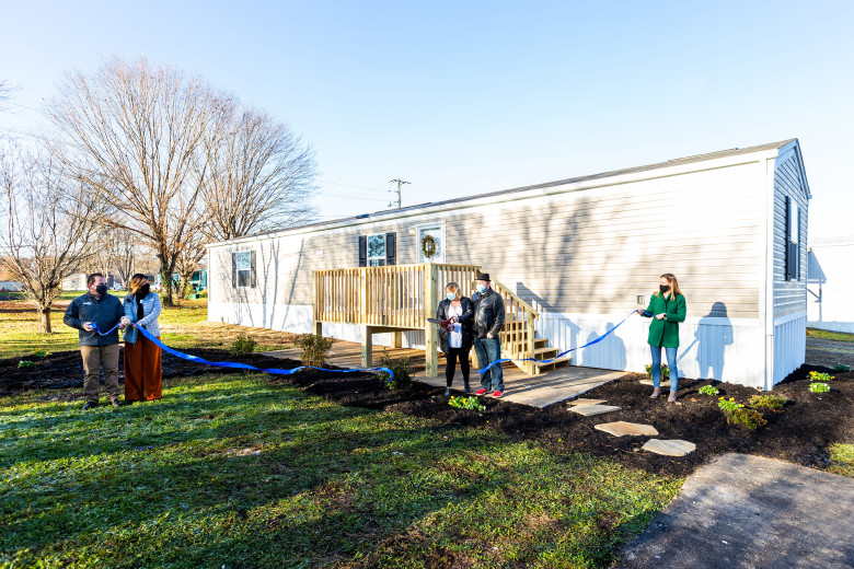 Representatives cut a ribbon in front of a new Clayton Built home that will be used as transitional housing.