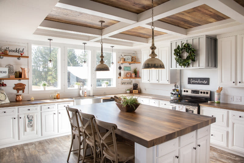 Kitchen of the Lulamae manufactured home with white cabinets, 3 windows, coffered wooden ceiling and island with wooden counters.