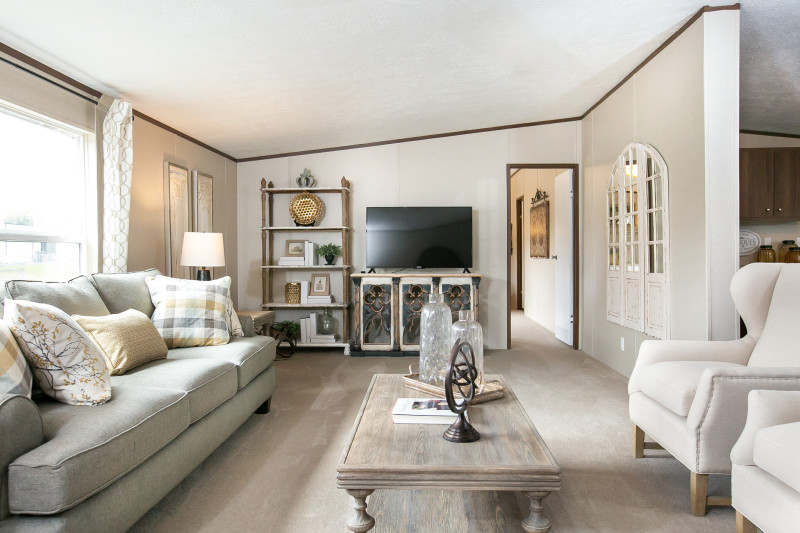 Living room of a Clayton manufactured home with neutral colored couches, chairs and décor, and cream carpet and walls.