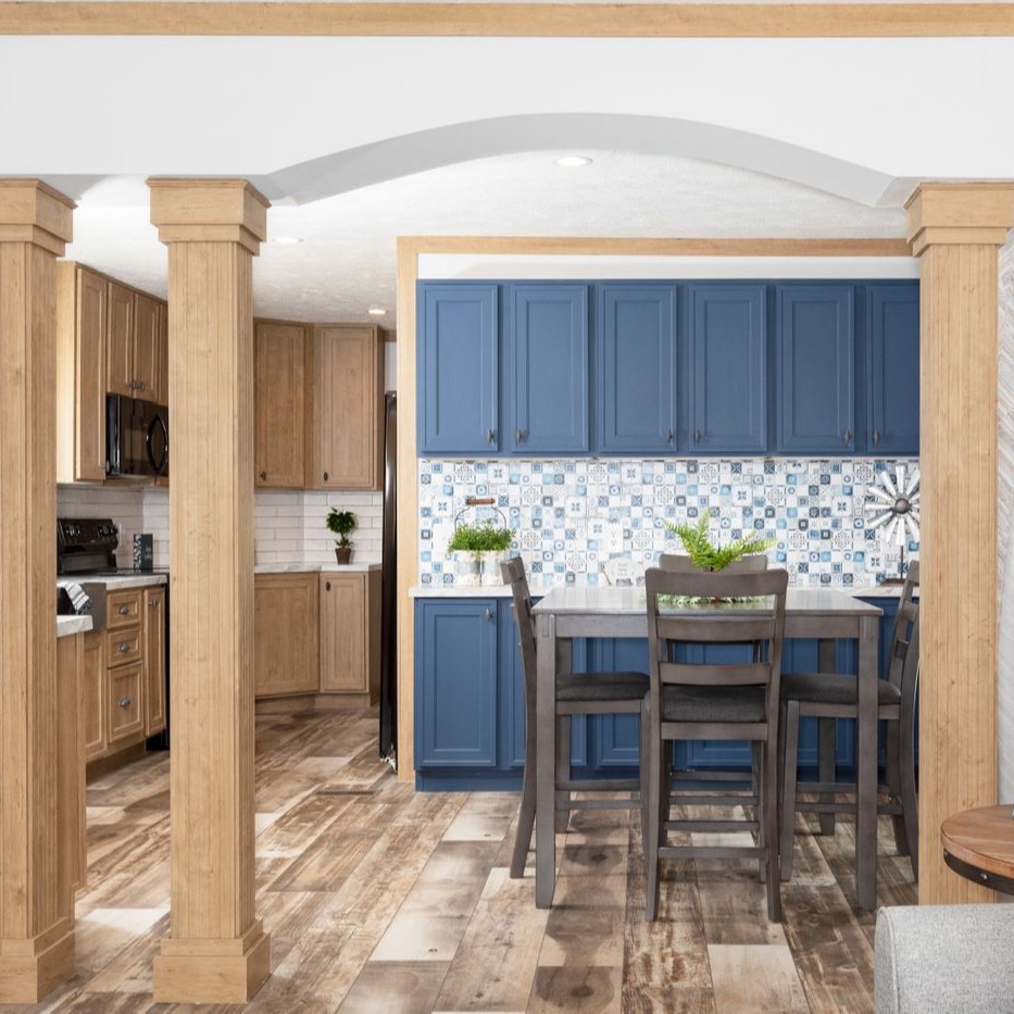The separate dining area of [model name] really shines with contrasting blue cabinets, patterned backsplash and the columns to the living space.