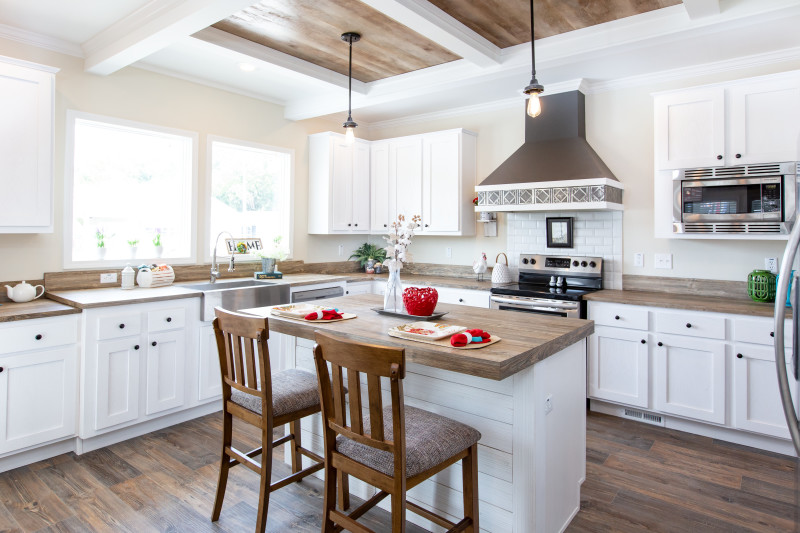 Kitchen of a farmhouse style manufactured Clayton home with white cabinets and wood floors and countertops.
