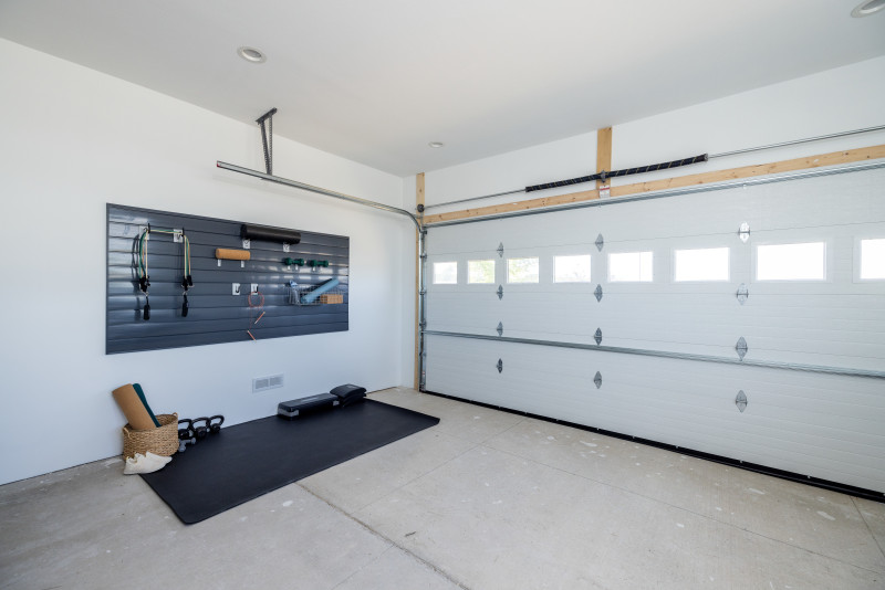 At-home gym area in a garage with a wall and a mat with gym equipment on it
