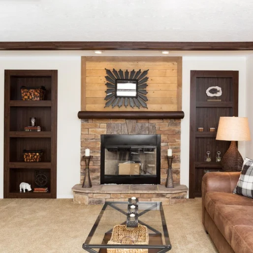 Tan and wood colors highlight this unique living room in our [model name] home. With a stone stack fireplace, open shelving and wood trim, this unique space stands out.