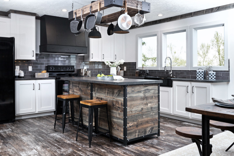 A large kitchen in a manufactured home with industrial-style accents, a kitchen island with distressed wood features and a gray subway tile backsplash.