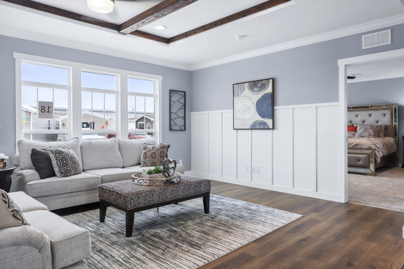 A manufactured home living room with gray walls, white wainscoting and dark wood flooring