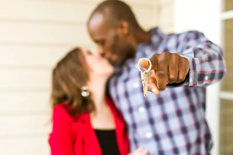 Man and woman holding keys to their new home.