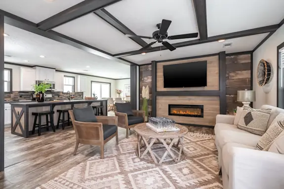 The [model name] features an open floor plan with an electric fireplace and huge kitchen island.