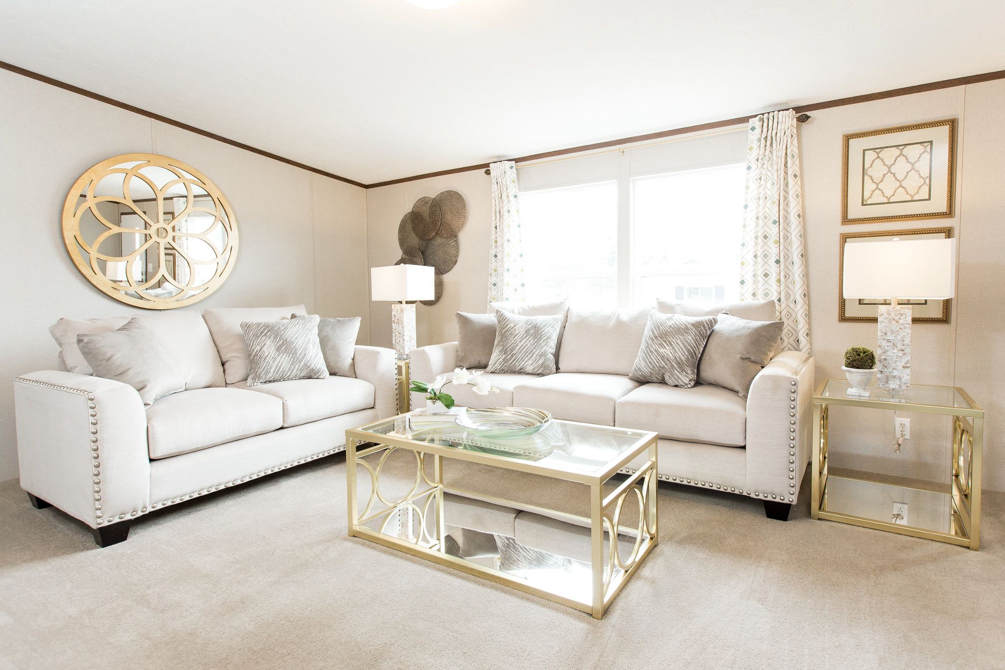  Crisp, white living room with white furniture and fresh off white accents, including a mirror over the couch. 