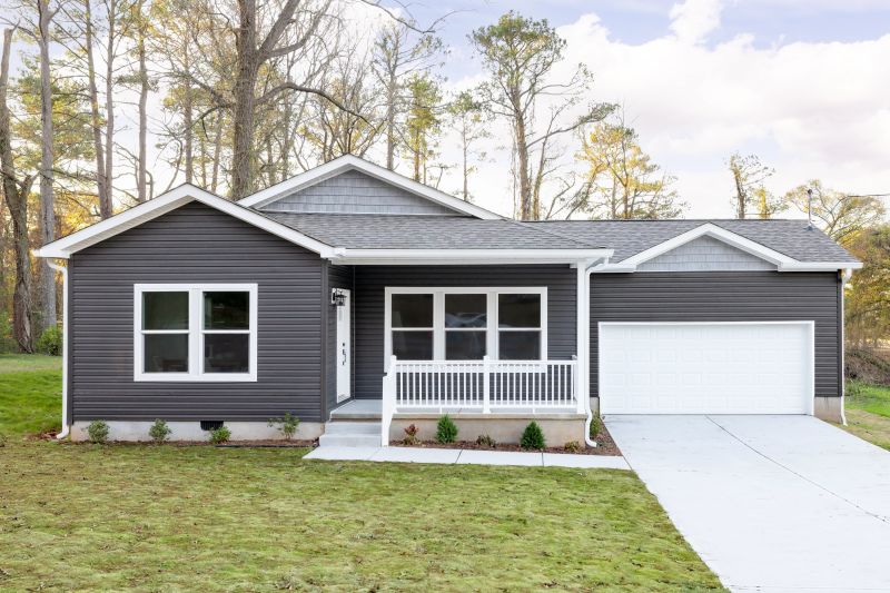Exterior of a Clayton CrossMod home with dark gray siding, porch, white trim and trees in the background.