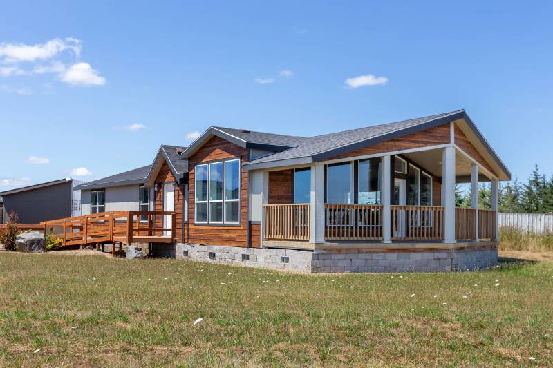 A manufactured home with wooden siding, a ramp and porch