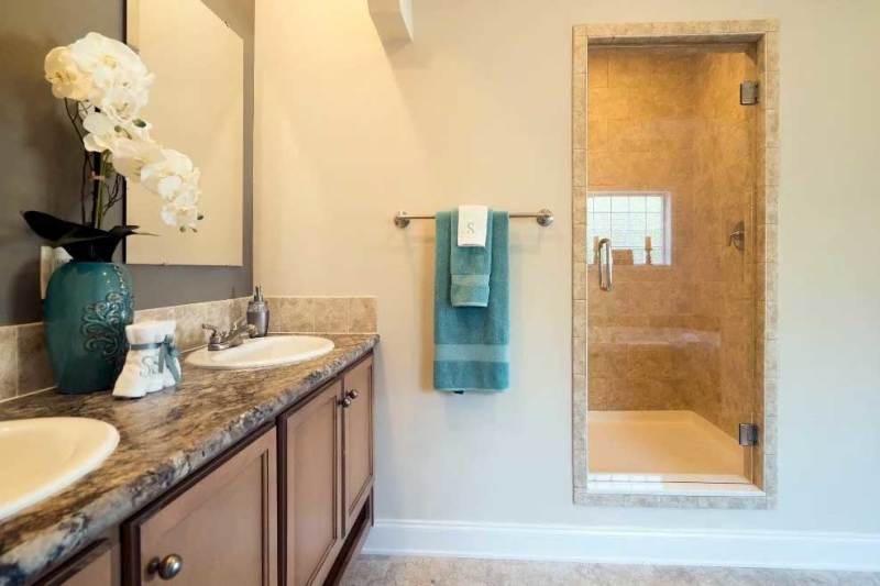 A manufactured home primary bathroom with a double-sink vanity and a large private shower