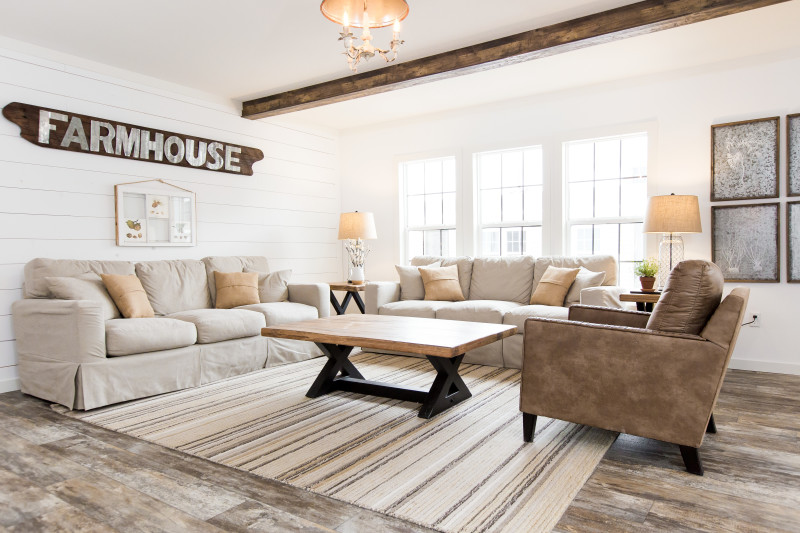 Cute farmhouse style living room with a wooden board above the couch that reads “Farmhouse”.