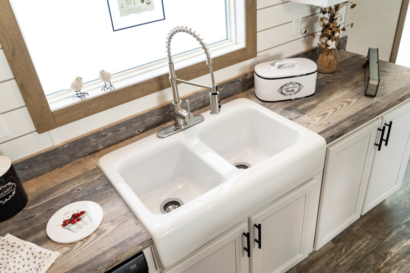  A white, double basin farmhouse sink in a kitchen