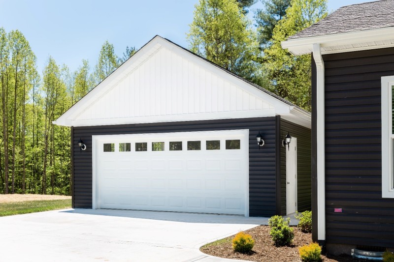 Detached garage next to a manufactured home with navy blue siding.