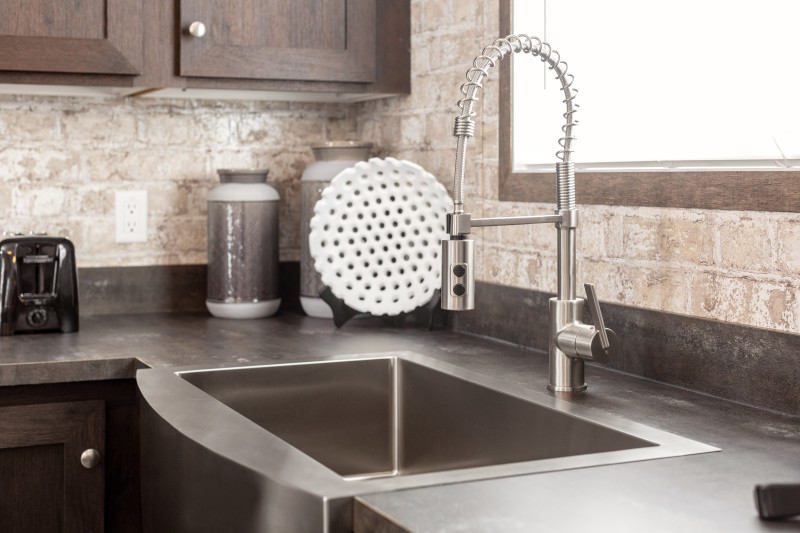 A single basin, stainless steel farmhouse sink in a kitchen